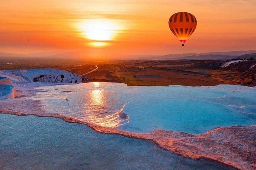 A hot air balloon over a landscape with reflective water at sunset. 4
