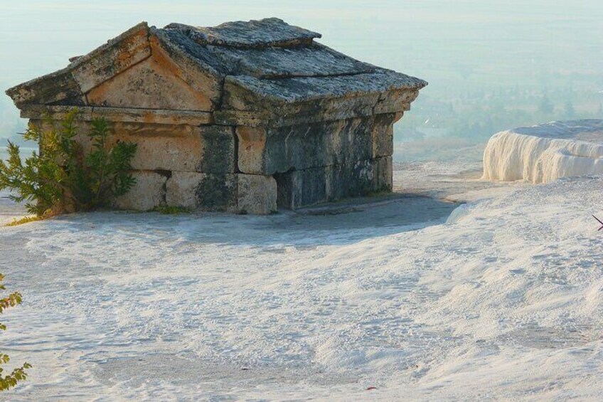 A stone building with a sloped roof, surrounded by snow-covered ground and a distant waterfall. 5
