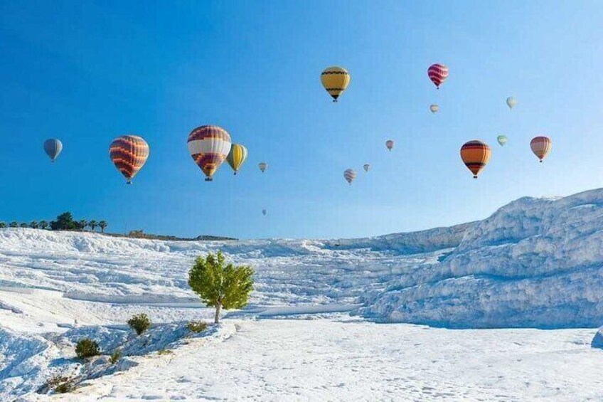 A snowy landscape with colorful hot air balloons in the sky. 1