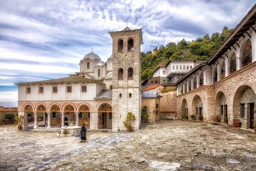 A historic stone building with a bell tower, arched windows, and a courtyard. 1