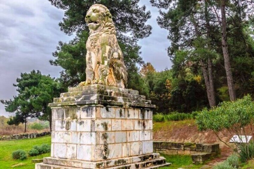 A stone lion statue on a pedestal in a park. 5