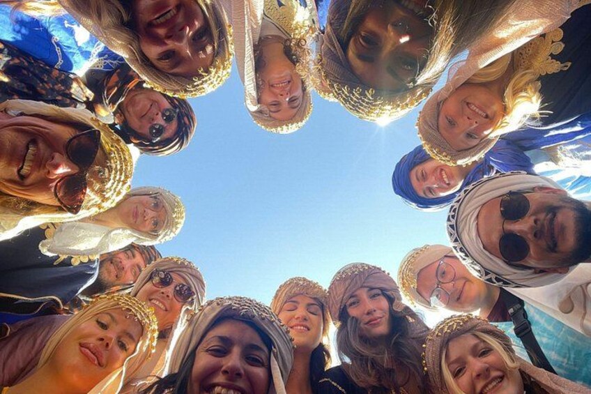 A group of people wearing traditional headgear and jewelry, gathered in a circle. 2
