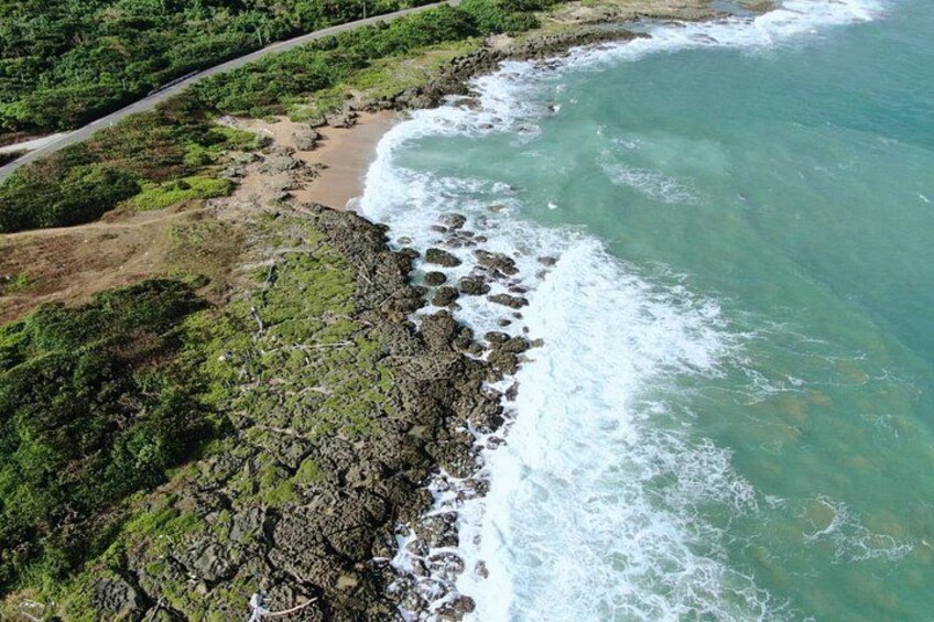 A coastal landscape with rocky cliffs, a sandy beach, and a winding road. 5