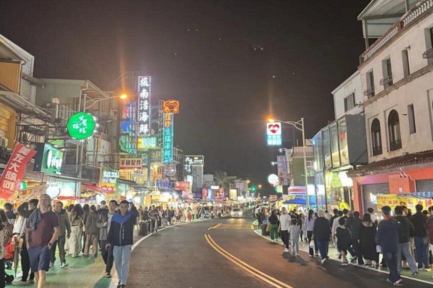 A crowded street at night with illuminated signs and buildings. 4