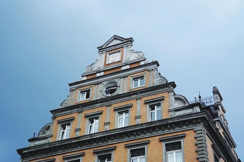 En bygning med flere etager, præget af detaljeret arkitektur, herunder et ur og dekorative elementer på facaden. 3