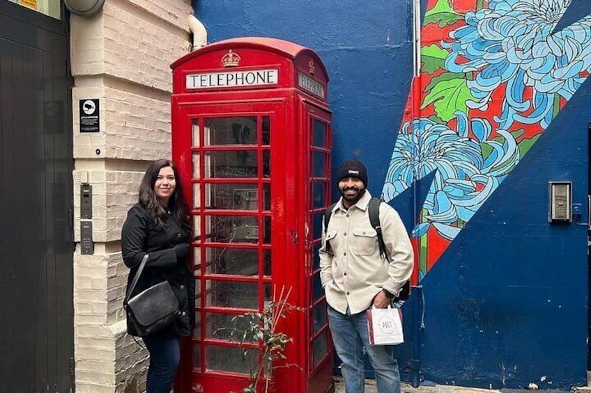 A red telephone booth, a person with a backpack, and a colorful mural on a blue wall. 3