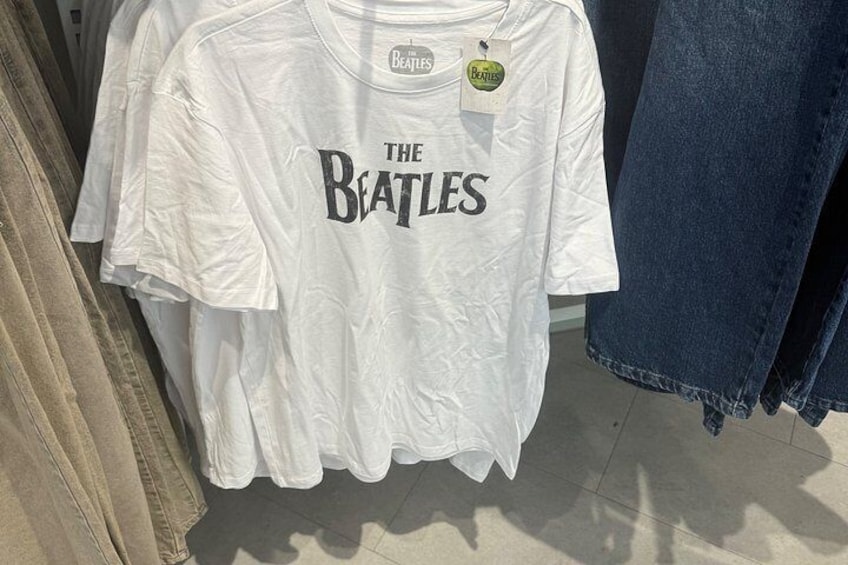 A white t-shirt with 'The Beatles' printed on it, hanging in a store. 5