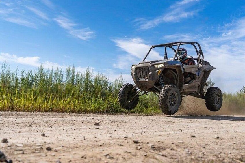 A four-wheeled off-road vehicle on a dirt road with vegetation on the side. 4