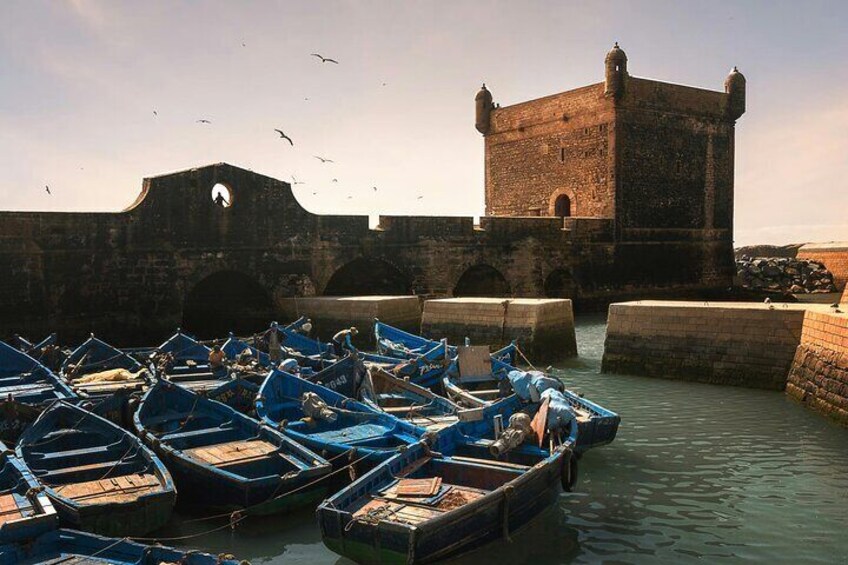 A harbor with boats docked near a historic stone tower. 2