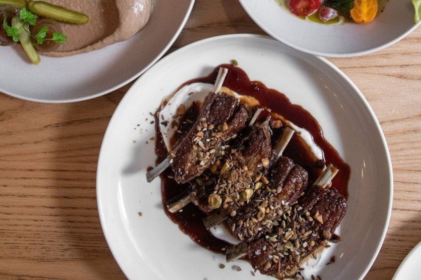 A plate of food with meat and sauce, garnished with seeds. 4