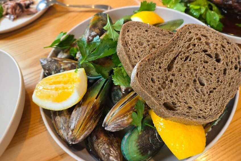 A plate of mussels, lemon wedges, parsley, and slices of brown bread. 5