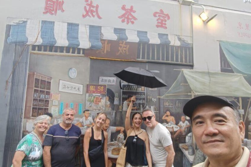 A group of people standing in front of a tea shop with a sign in a foreign language. 2