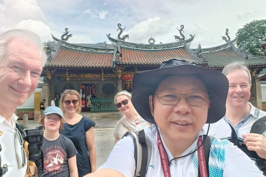 A group of people in front of a traditional Chinese building with ornate roofs and a red and gold facade. 5