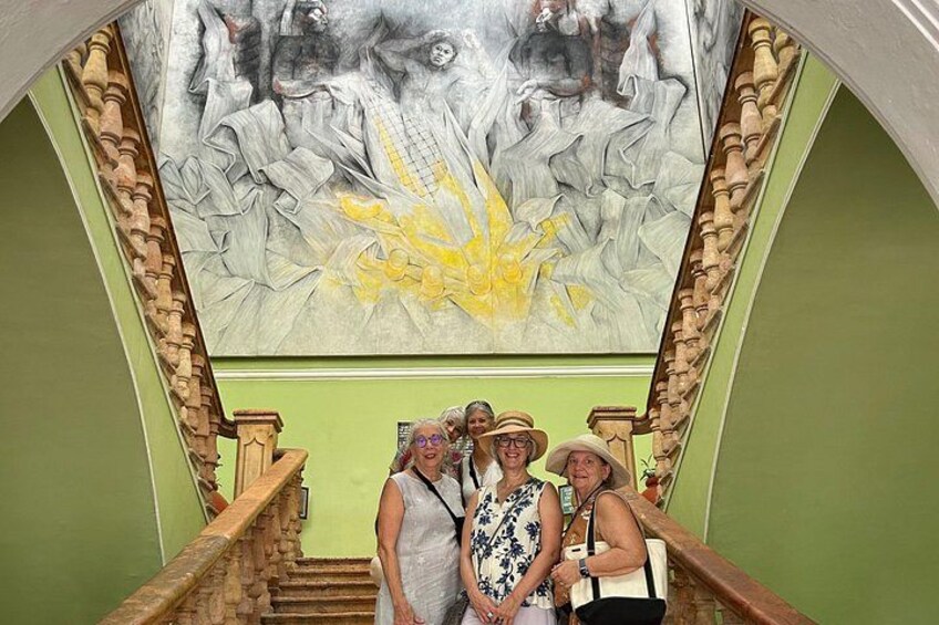 A staircase with a mural above it, a wooden handrail, and a green wall. 2