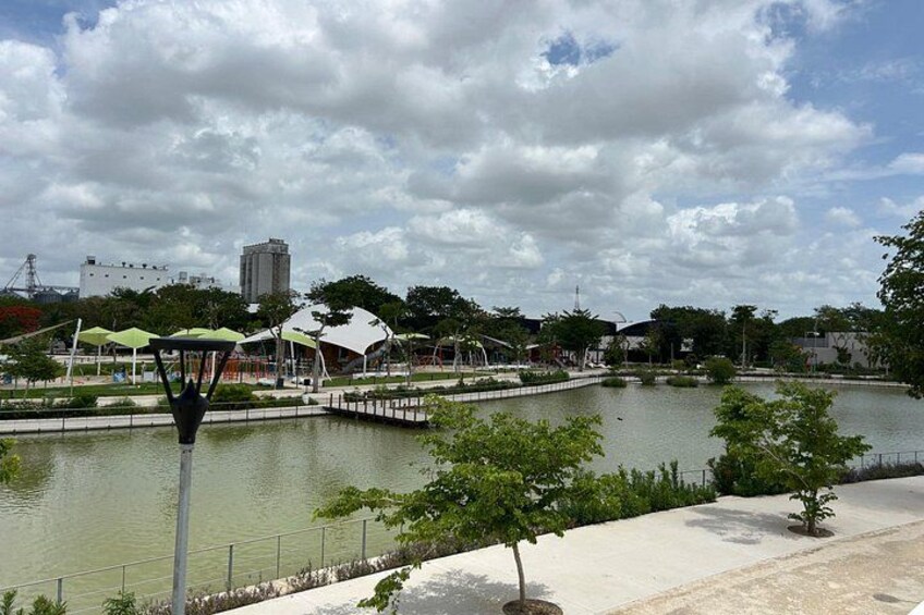 A riverside park with a walking path, trees, and a bridge. 5