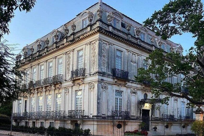 A large, ornate building with classical architecture, featuring multiple balconies and a symmetrical facade. 1