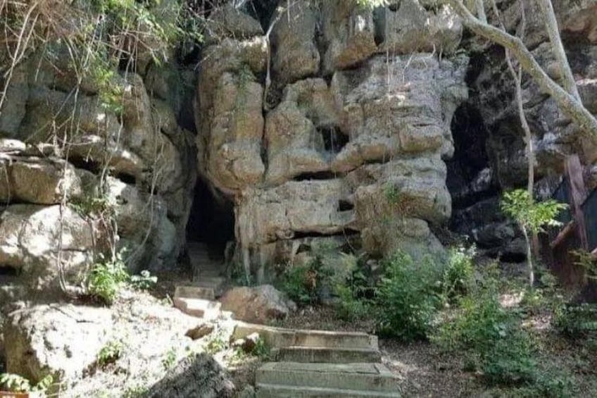 A rocky cave entrance with steps leading up to it. 5