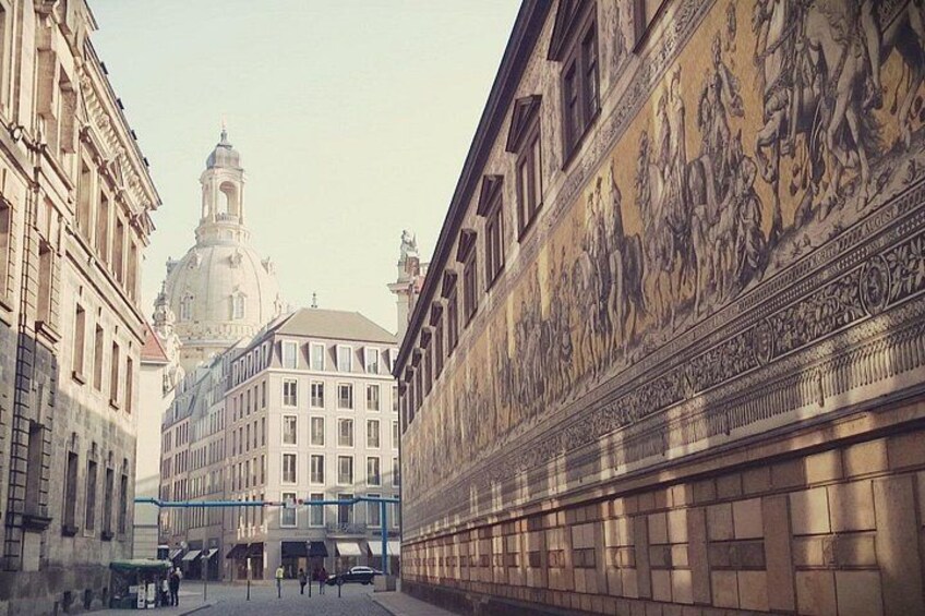 Une rue bordée d’immeubles à l’architecture classique, surmontée d’un dôme et agrémentée d’une fresque murale richement décorée. 5