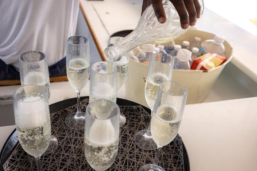 A person pouring a clear liquid into several glasses on a table. 2