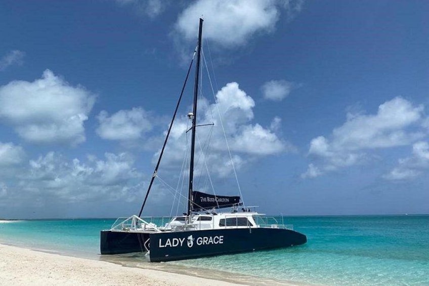 A sailboat named 'Lady Grace' docked on a beach with clear turquoise waters and a clear sky. 3