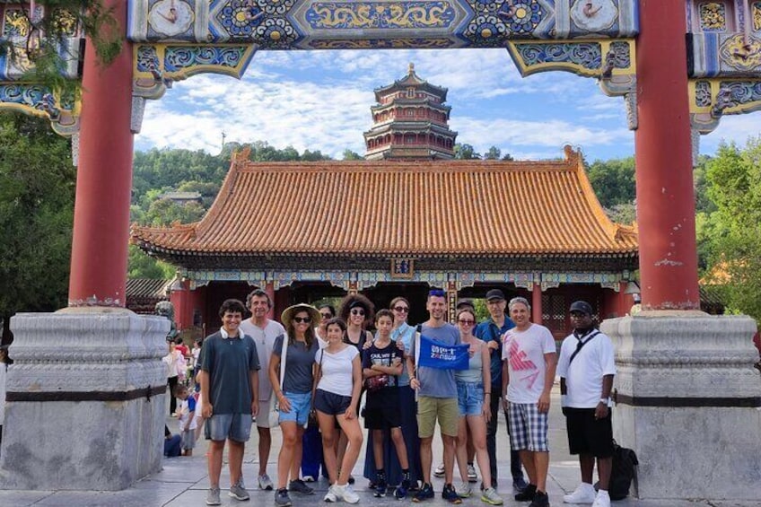 A group of people standing in front of a traditional Chinese gate with a pagoda in the background. 1