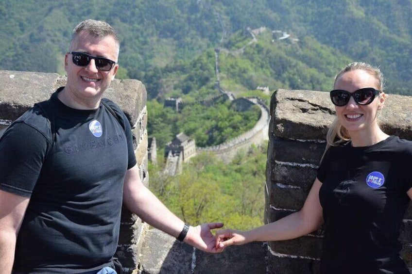 Two people standing on a stone wall with a view of a historical site in the background. 2