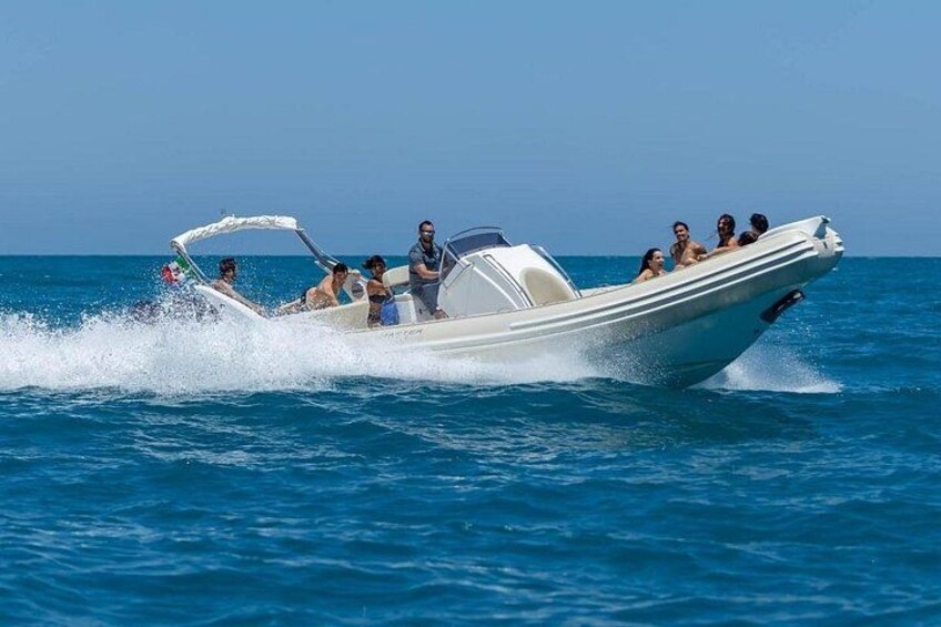 Un barco a motor blanco con gente a bordo, navegando sobre aguas azules. 5