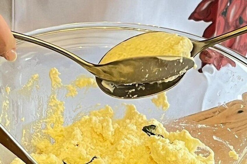 A person scooping yellow batter from a mixing bowl. 2