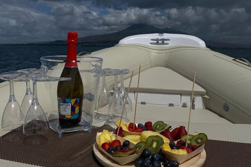Un barco con una botella de vino, copas y una bandeja de frutas sobre una mesa. 3