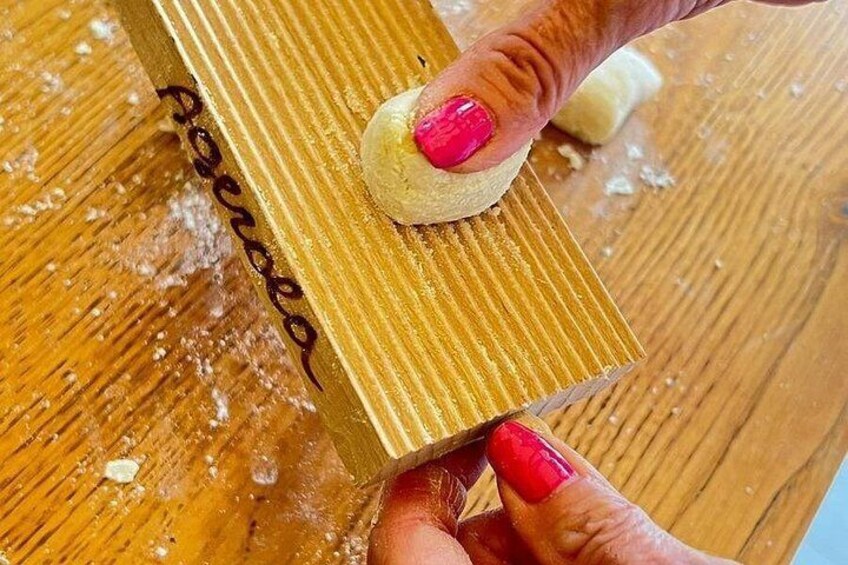A hand holding a wooden block with a white object on top, possibly a cookie or pastry, with a dusting of flour around. 4