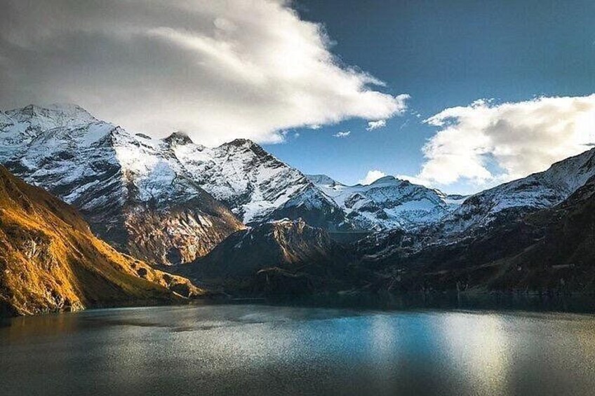 A mountain landscape with snow-capped peaks, a clear sky, and a calm lake. 2