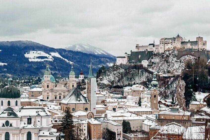 A snow-covered cityscape with historic buildings and a castle on a hill. 3