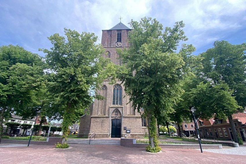 A church with a tall tower, surrounded by trees and a paved walkway. 5