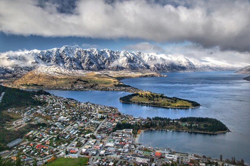 En kuststad med en hamn, en liten ö och snöklädda berg i bakgrunden. 1