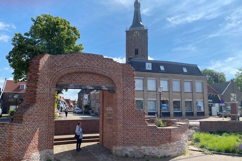 A brick archway, a church with a clock tower, and a building with a sign. 5