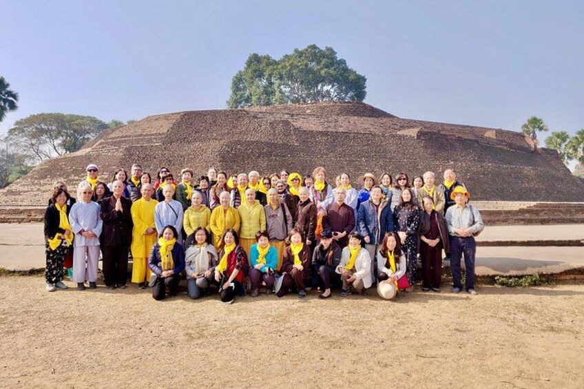 A group of people posing in front of a large mound-like structure. 2