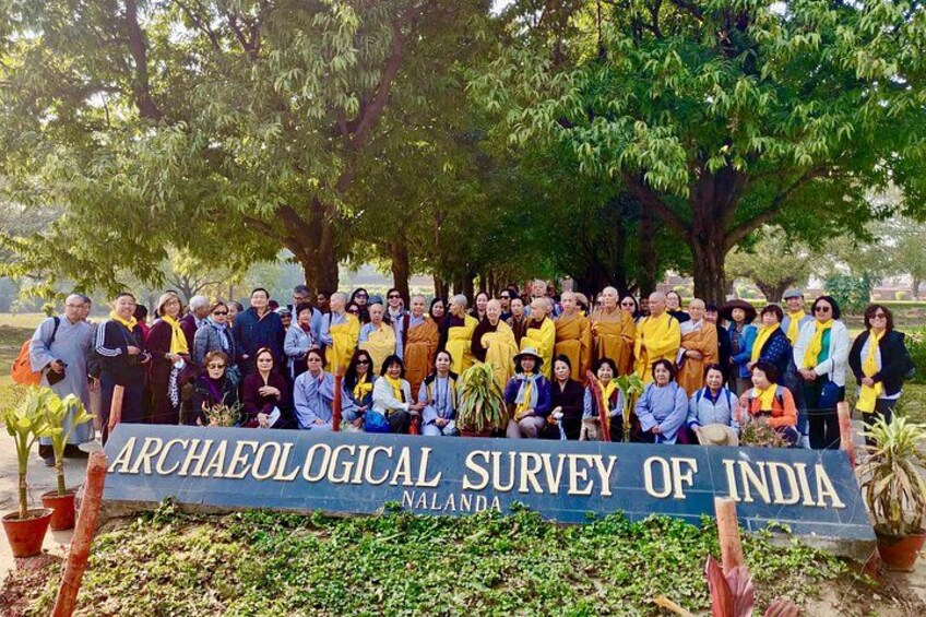 A group of people posing in front of a banner for the Archaeological Survey of India in Nalanda. 3