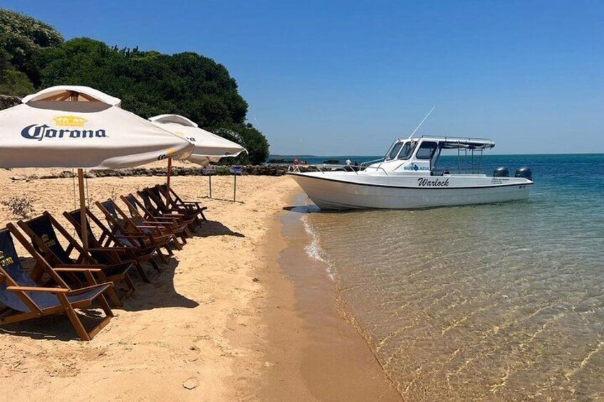 Una playa con sillas de descanso, un bote y sombrillas de Corona. 5