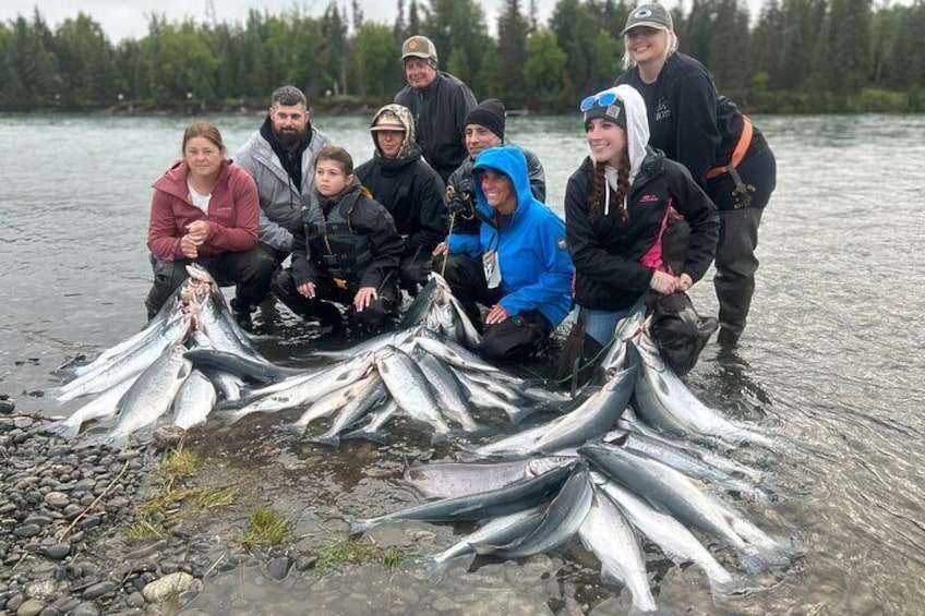 A group of people holding fish by a river. 4