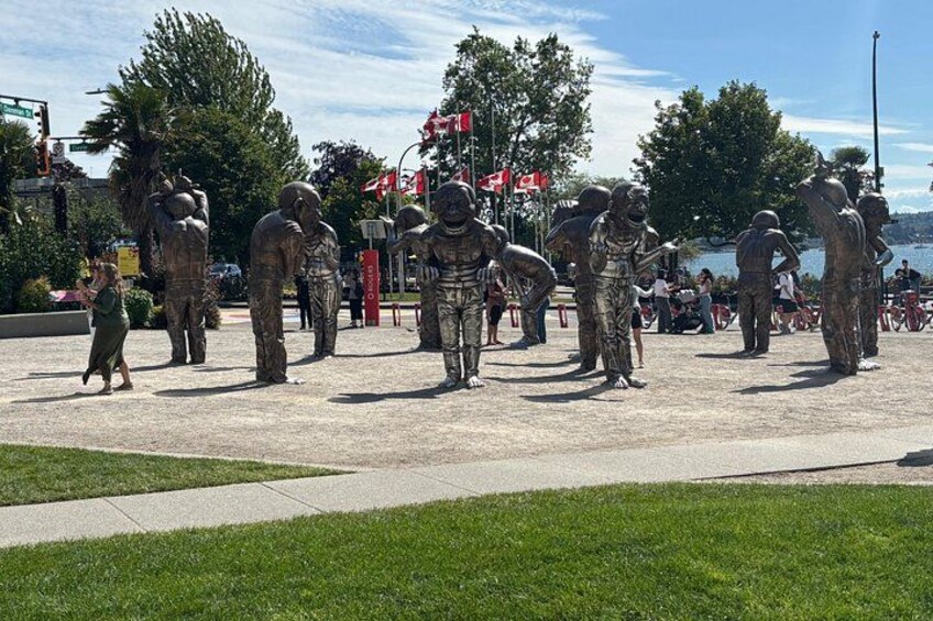 Una escultura de soldados con uniforme, un área con césped y una masa de agua al fondo. 5