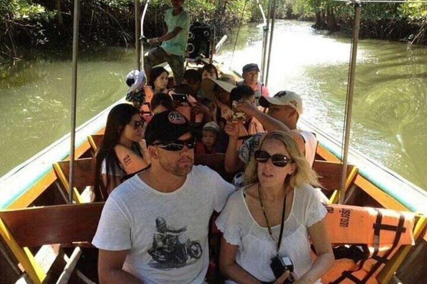 Eine Gruppe von Menschen auf einem Boot in einem von Bäumen gesäumten Fluss. 2