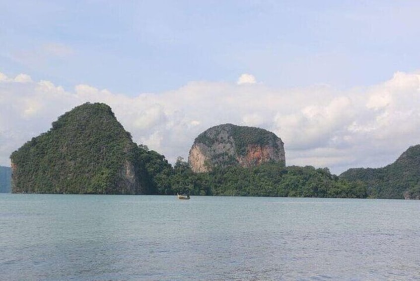A calm sea with two prominent green islands and a boat in the distance. 5