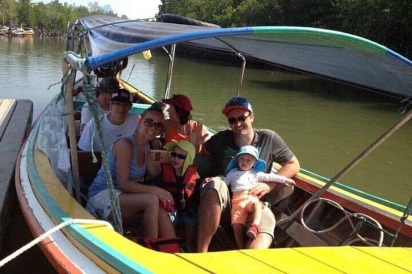 Eine Familie auf einem kleinen Boot mit Verdeck, umgeben von ruhigem Wasser und viel Grün. 4