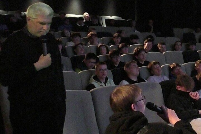 A person standing in front of an audience in a theater. 3