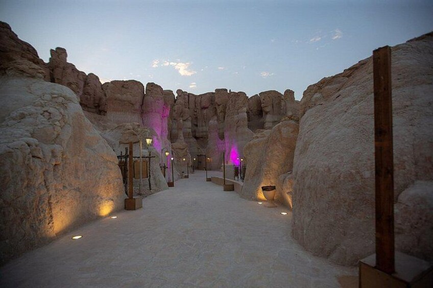 A snow-covered pathway flanked by rock formations with illuminated lanterns. 3