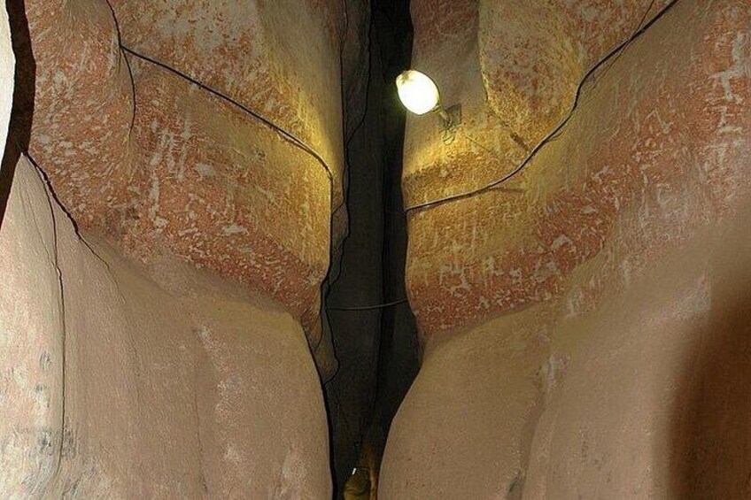 A textured wall with a light fixture and a crack running through it. 2