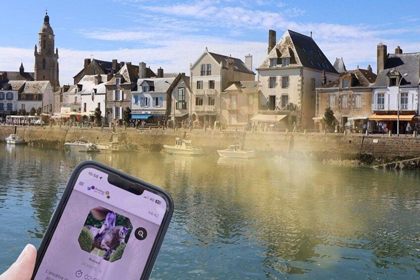 En smartphone viser et billede af en historisk by med bygninger og en flod. 1