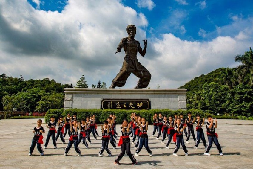 Un groupe de personnes exécutant une danse synchronisée devant une grande statue. 2