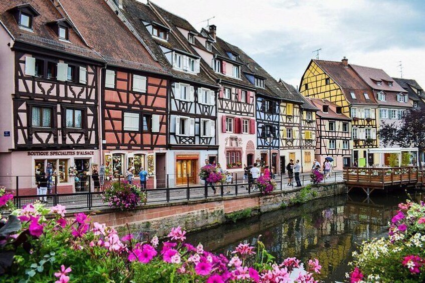 A canal with buildings on one side and flowers in the foreground. 1