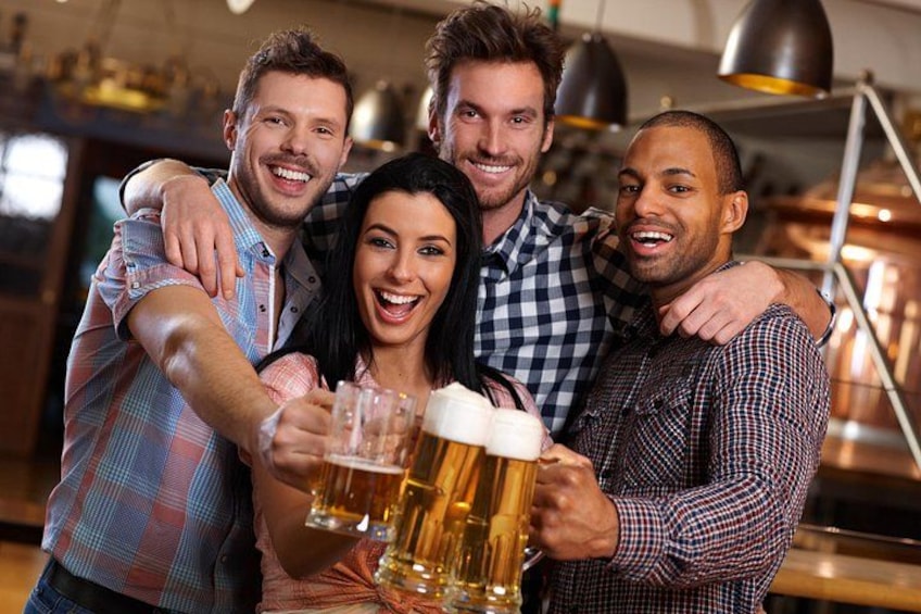A group of people toasting with beer glasses in a bar setting. 3